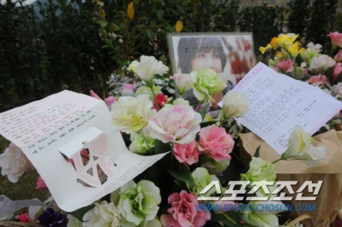 Tại địa điểm diễn ra buổi lễ, người hâm mộ và người thân trong gia đình đều đem tới rất nhiều hoa, ảnh của cố nghệ sĩ. 