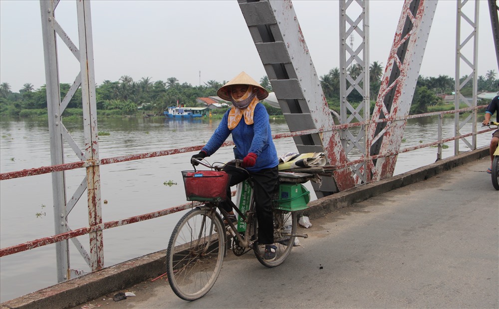 Người dân nghèo đi xe đạp mưa sinh đi về qua cây cầu.