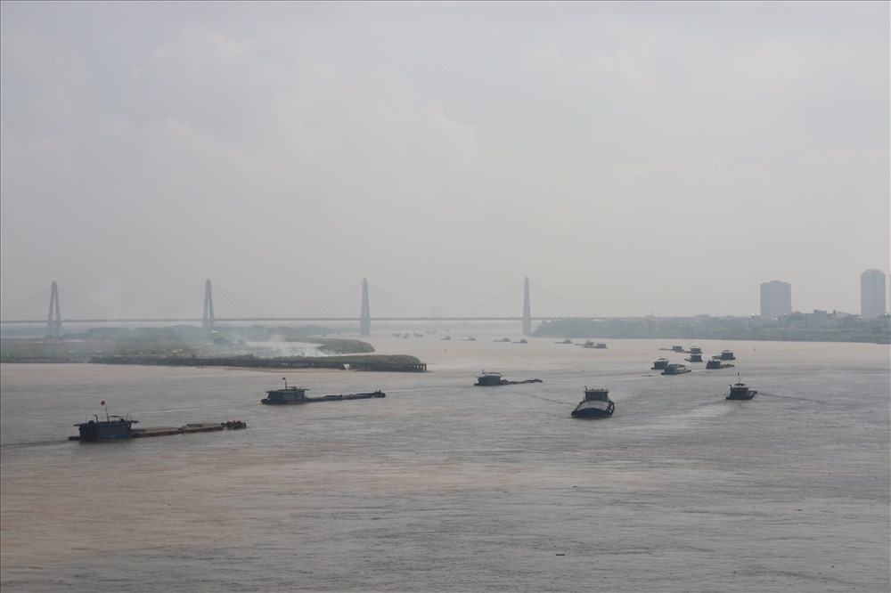 Quan sát từ Cầu Thăng Long, các tàu chở vượt tải trọng như “dàn trận” trên sông Hồng. Sự qua mặt trắng trợn lực lượng chức năng đặt ra nhiều vấn đề trong quản lý vận tải đường thủy. Ngay từ khâu bốc xếp hàng, vật liệu tại bến cảng trong nội địa đến giám sát việc lưu thông của các phương tiện.