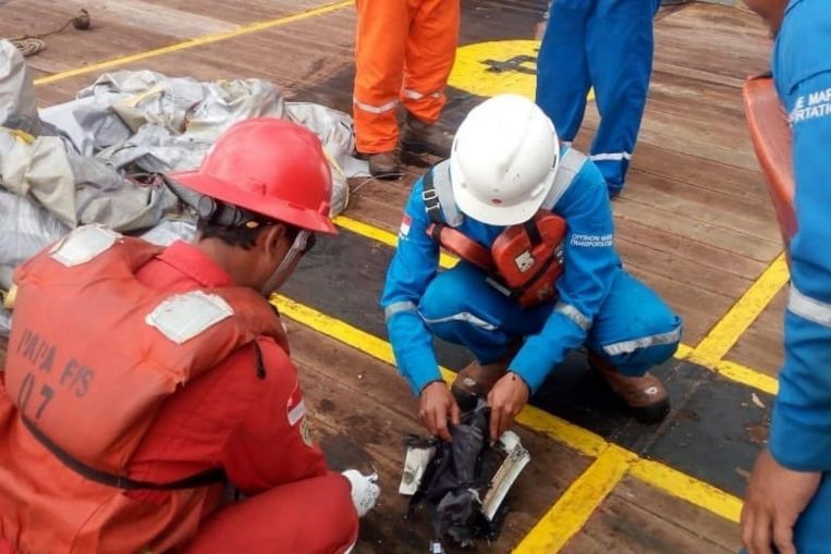 Nhân lực từ công ty Pertamina đang kiểm tra các mảnh vỡ tìm thấy từ hiện trường máy bay rơi. Ảnh: ST. 