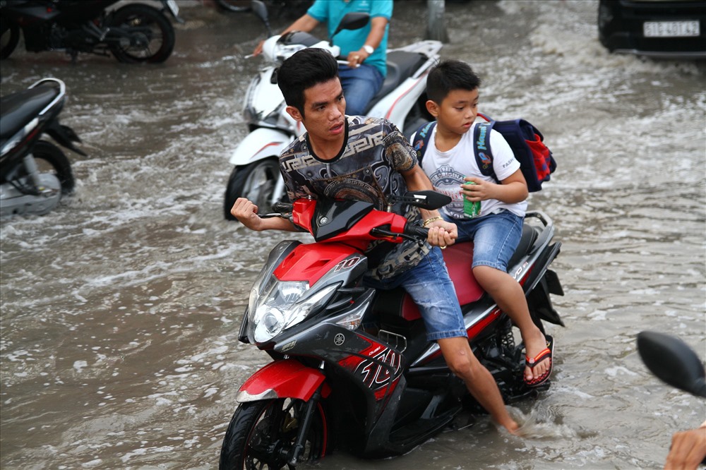 Triều cường dâng vào giờ tan tầm khiến người dân đi lại khó khăn.