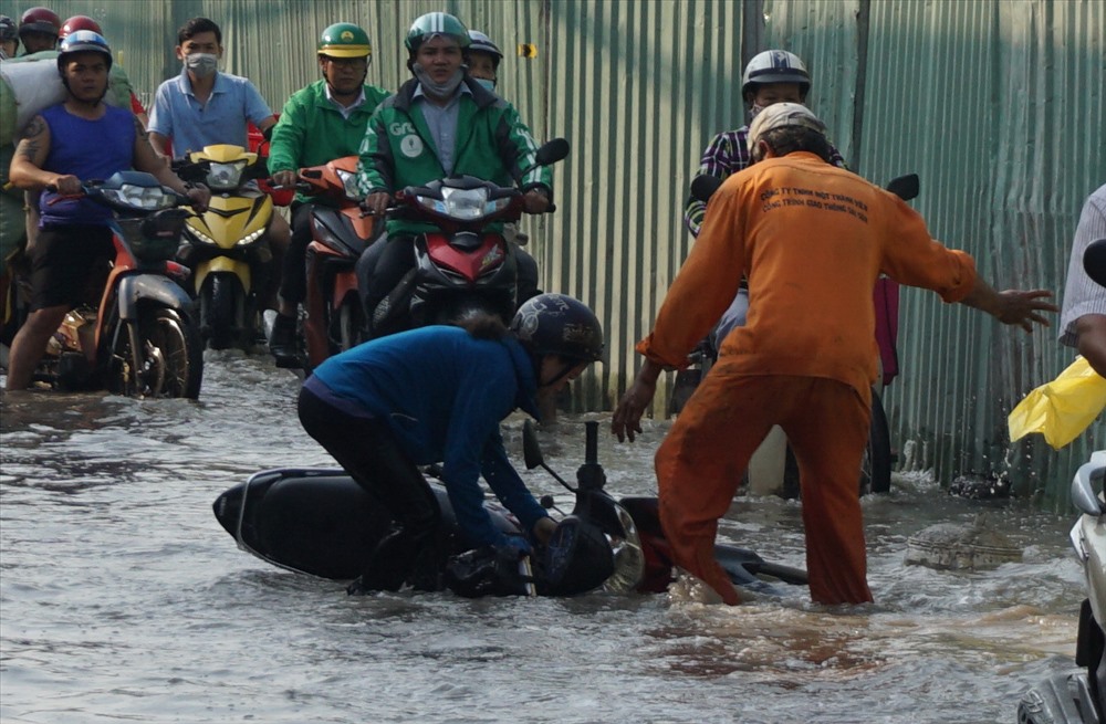 Công nhân công trình trên đường Huỳnh Tấn phát giúp một phụ nữ ngã xe dựng xe máy lên.