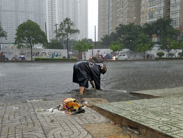 Người dân trên đường Nguyễn Hửu Cảnh đang đang vét những rác thải gây cản trở thoát nước