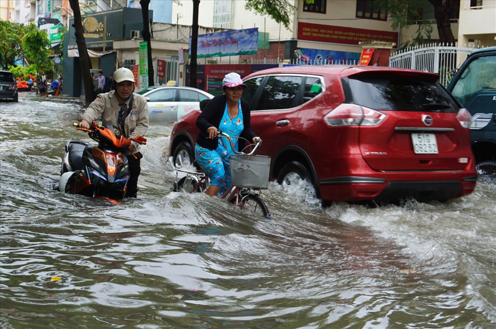 Nhiều ô tô chạy qua đường ngập tao sóng lớn khiến người đi xe máy chao đảo.