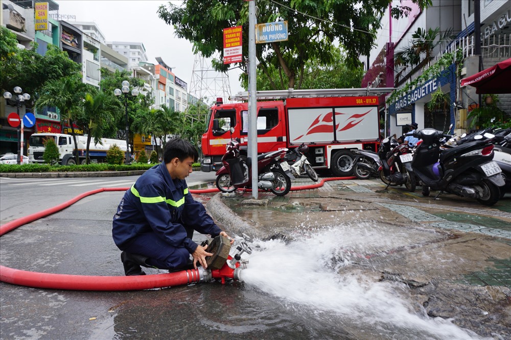Lực lượng cứu hộ tiến hành bơm nước ra khỏi hầm tòa nhà ra đường.
