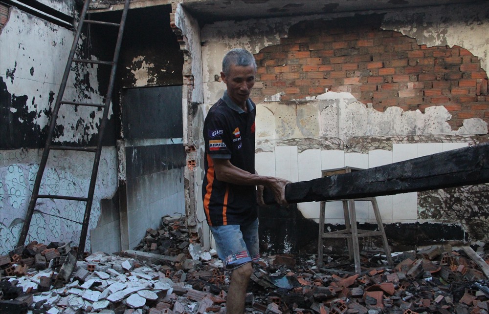 Ông Trương Văn Sút, tự tay dỡ cây đòn  tay của căn nhà bị cháy xém hư hỏng.