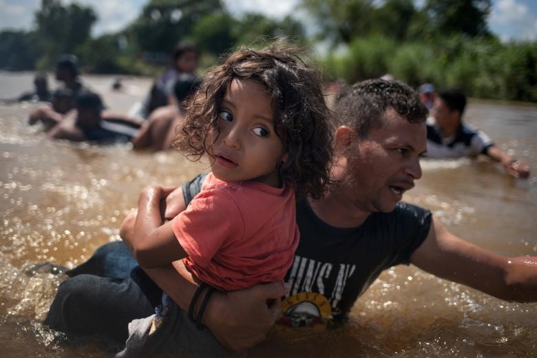 Luis Acosta cùng cô bé Angel Jesus 5 tuổi (Honduras) di cư từ Trung Mỹ trên đường đến Hoa Kỳ băng qua sông Suchiate vào Mexic, ngày 29 tháng 10. Ảnh: REUTERS 