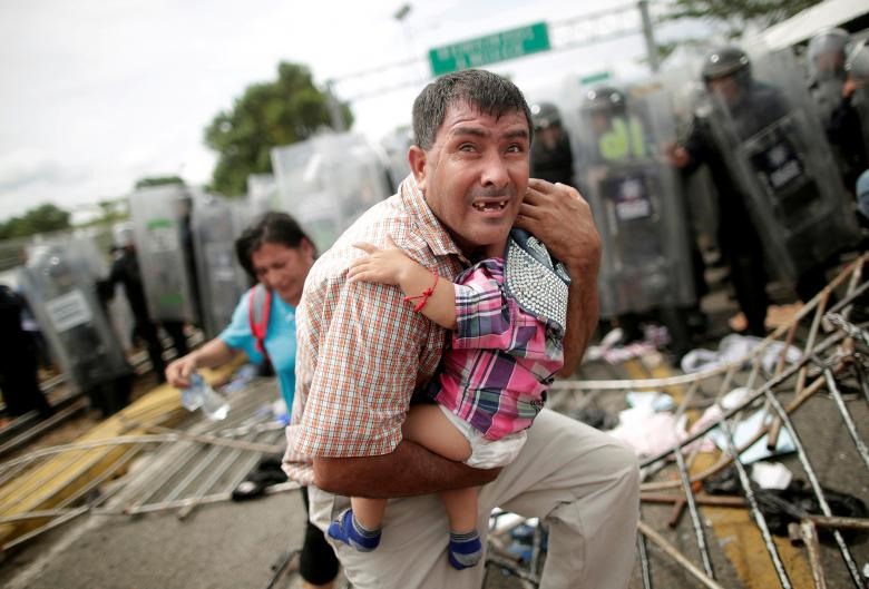  Một người di cư Honduras ôm chặt đứa con của mình khi lực lượng an ninh cố gắng ngăn cản đoàn người di cư đang xông vào một trạm kiểm soát biên giới ở Guatemala. 