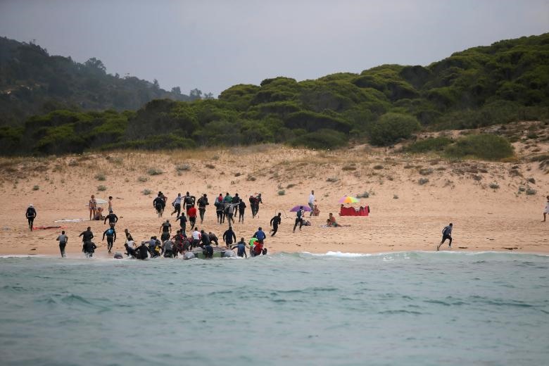 Những người di cư lên bờ từ bãi biển Del Canuelo sau khi họ vượt qua Eo biển Gibraltar từ bờ biển Morocco, ở Tarifa, miền nam Tây Ban Nha. Ảnh: Reuters.