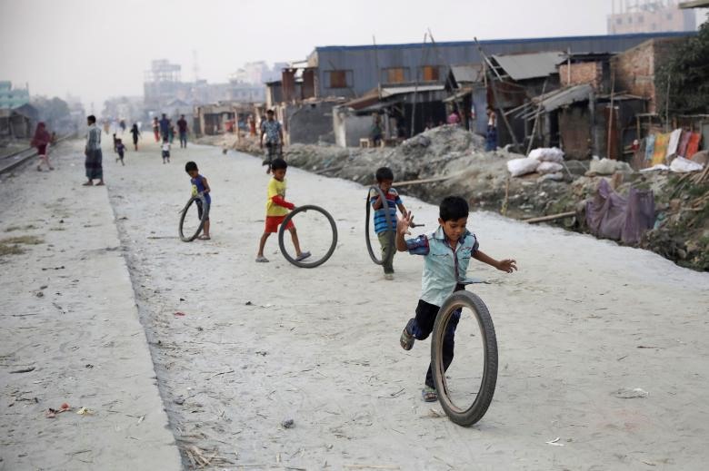 Những đứa trẻ thích thú vui đùa với lốp xe dọc theo một con phố ở Dhaka, Bangladesh. Ảnh: REUTERS.