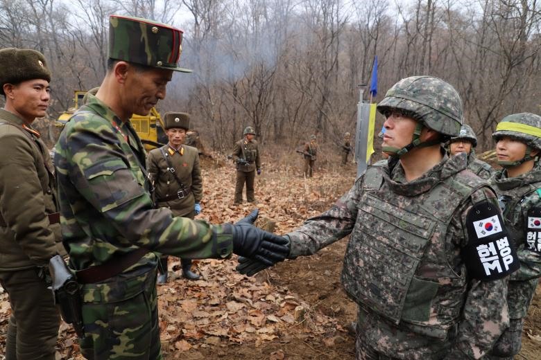 Một sĩ quan quân đội Hàn Quốc (R) và một sĩ quan quân đội Bắc Triều Tiên bắt tay trong một hoạt động để kết nối lại một con đường xuyên qua Đường phân giới quân sự bên trong Khu phi quân sự (DMZ) tách hai miền Triều Tiên, ngày 22 tháng 11. Ảnh: REUTERS.