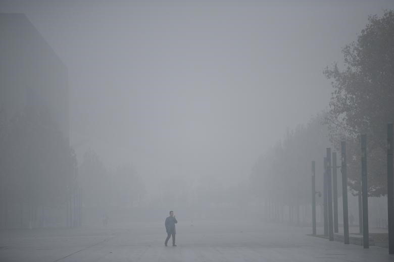 Người ông đi giữa sương mù ở Thiên Tân mặc dù trước đó, thành phố đã ban hành một cảnh báo về mức độ ô nhiễm không khí ở Trung Quốc. Ảnh: REUTERS.