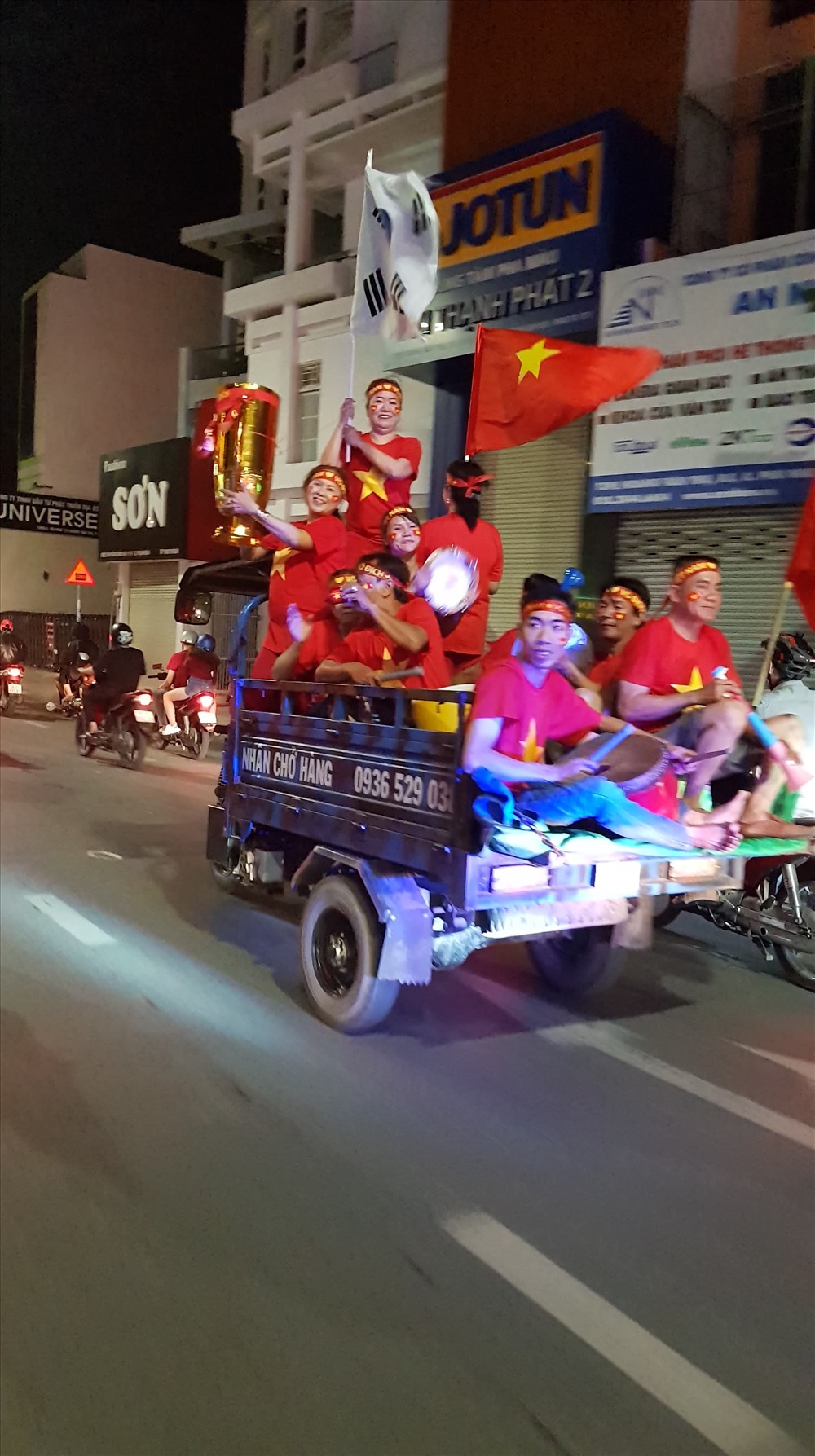 Trên đường Nguyễn Kiệm, Phú Nhuận, cả một gia đình đi “bão” bằng xe ba gác máy, giương cao chiếc cúp tự chế.