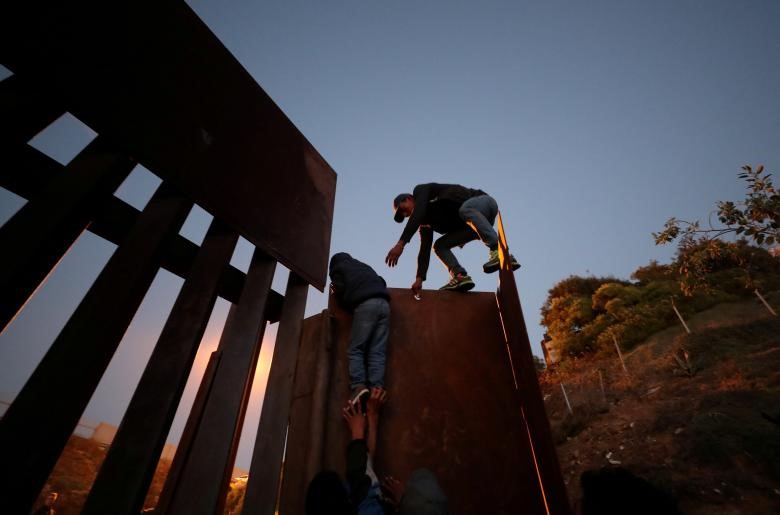 Những người di cư từ Honduras, một phần của một đoàn gồm hàng ngàn người từ Trung Mỹ đang cố gắng đến Hoa Kỳ, cố gắng trèo qua một hàng rào biên giới.