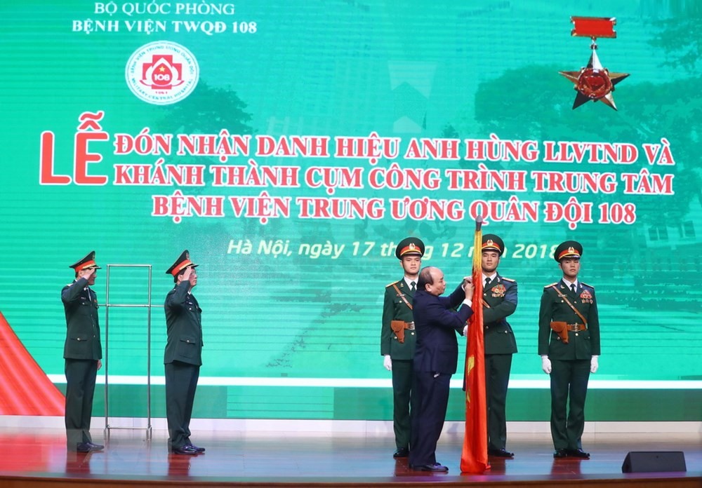 Thủ tướng Nguyễn Xuân Phúc gắn Danh hiệu Anh hùng lực lượng vũ trang Nhân dân thời kỳ kháng chiến chống Pháp lên lá cờ truyền thống của Bệnh viện Trung ương Quân đội 108. (Ảnh: Thống Nhất/TTXVN)