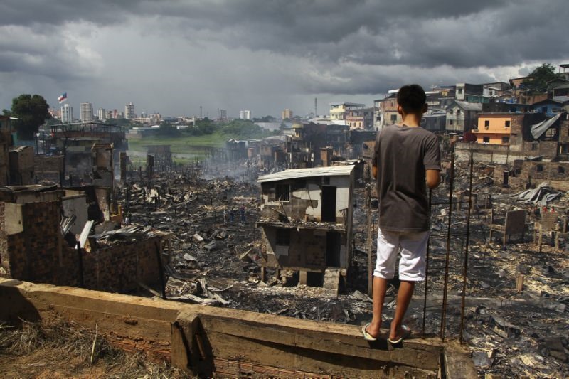 Một người đàn ông đứng ở khu phố Educandos, Manaus, Brazil sau đám cháy. Ảnh: AP.
