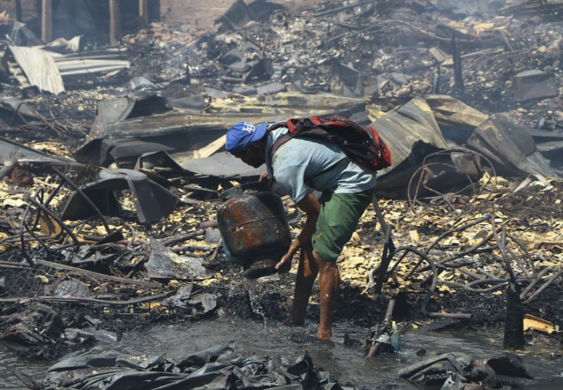 Một người dân tìm lại tài sản cá nhân còn lại trong tro tàn sau đám cháy ở Manaus, Brazil. Ảnh: AP. 