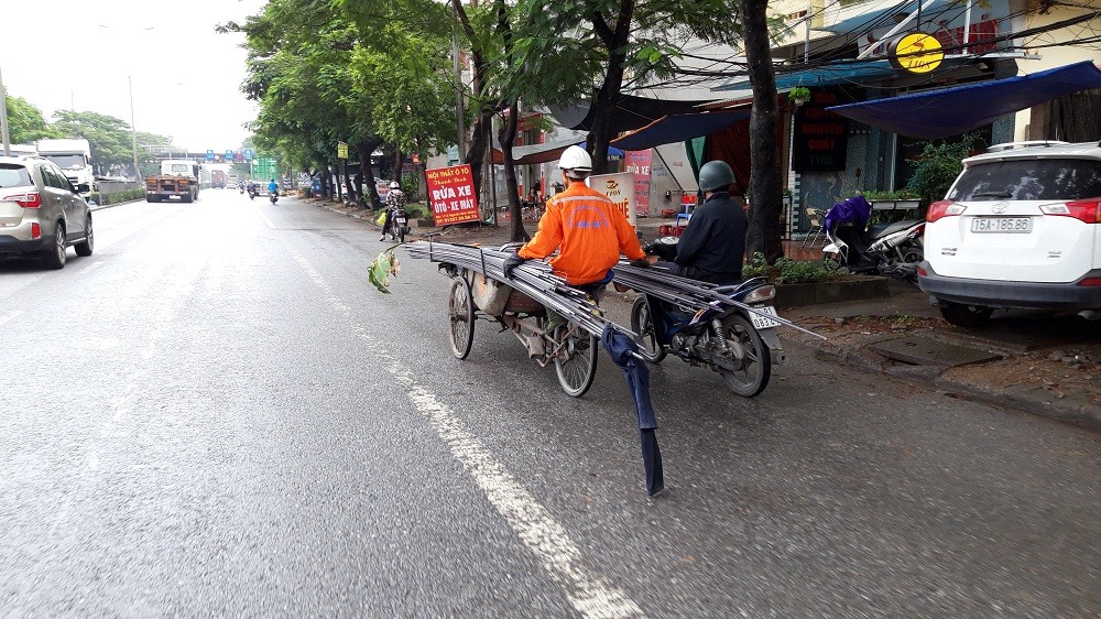 Xe máy đẩy xích lô chở sắt thép trên đường Nguyễn Văn Linh. Ảnh: PV.