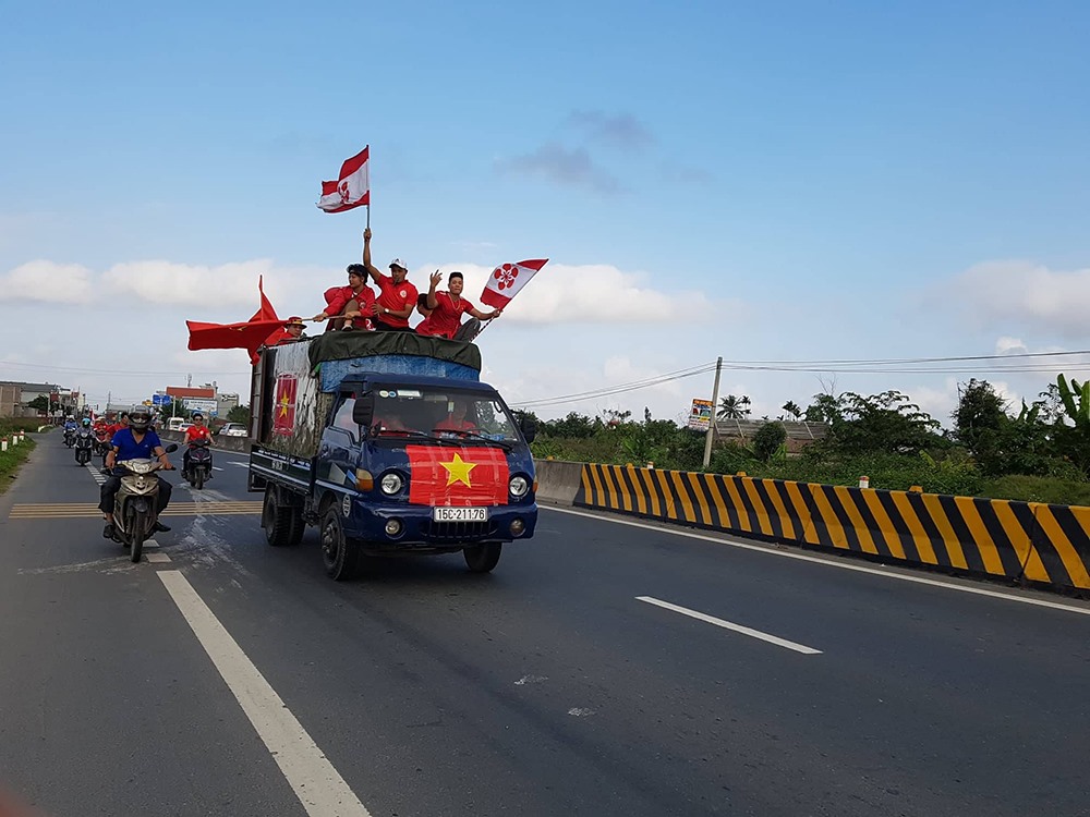 Chiếc xe tải chở rất đông cổ động viên được gắn cờ tổ quốc và cờ Hội cổ động viên  đi giữa đoàn diễu hành. 