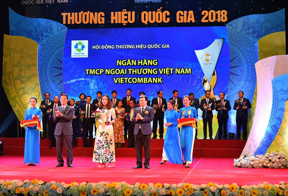Phó Tổng giám đốc Vietcombank Nguyễn Thị Kim Oanh nhận Biểu trưng và hoa chúc mừng từ Phó Thủ tướng Chính phủ Trịnh Đình Dũng và Bộ trưởng Bộ Công thương Trần Tuấn Anh