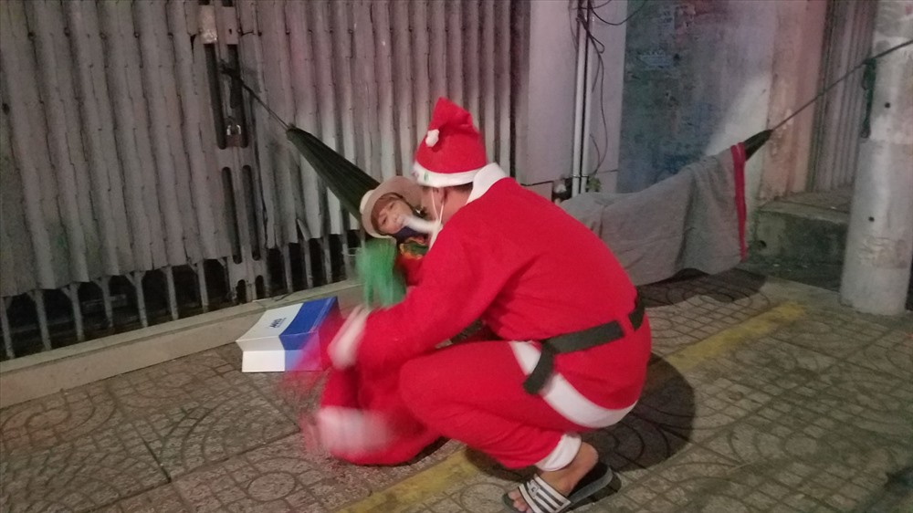 Ông già Noel đang mang suất quà biếu cho bà cụ bên đường. Suất quà gồm: 1 phần bánh mỳ thịt, sữa tươi hoặc nước suối.