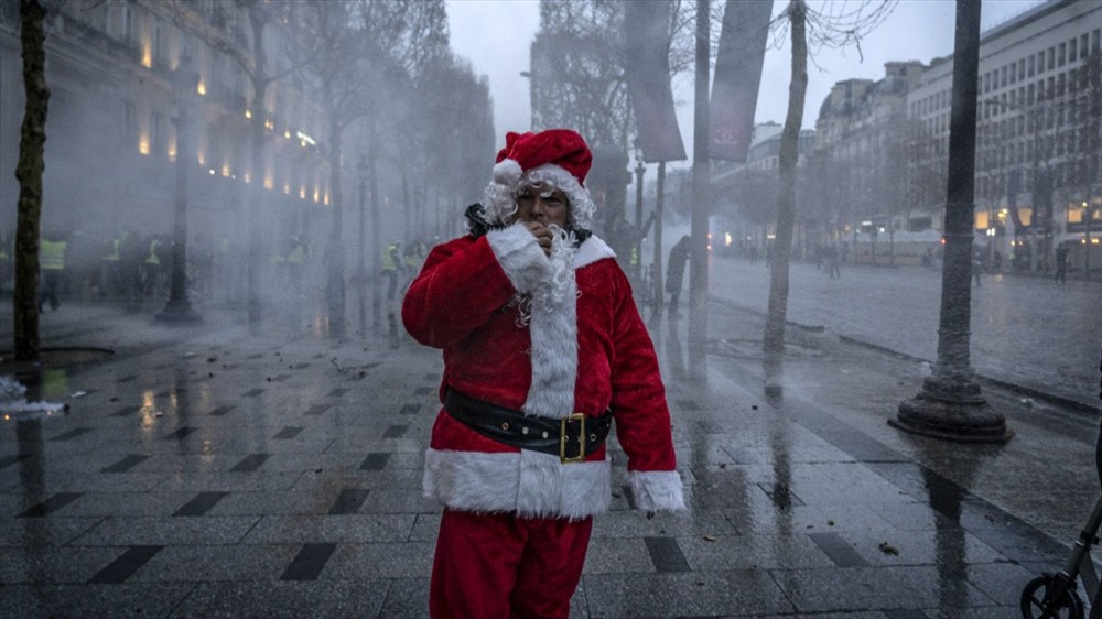 Tháng 12: Một người đàn ông trong trang phục ông già Noel trên đường phố Paris khét lẹt khói trong cuộc biểu tình của phe Áo gile vàng phản đối chính sách của Tổng thống Emmanuel Macron. Ảnh: Getty Images