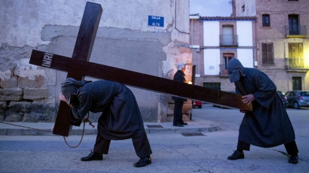 Tháng 3: Một người sám hối tròng sợi dây qua cổ vác thánh giá trong Lễ Thứ năm Tuần thánh (Maundy Thursday) ở làng Sietamo, phía bắc Tây Ban Nha. Ảnh: AFP