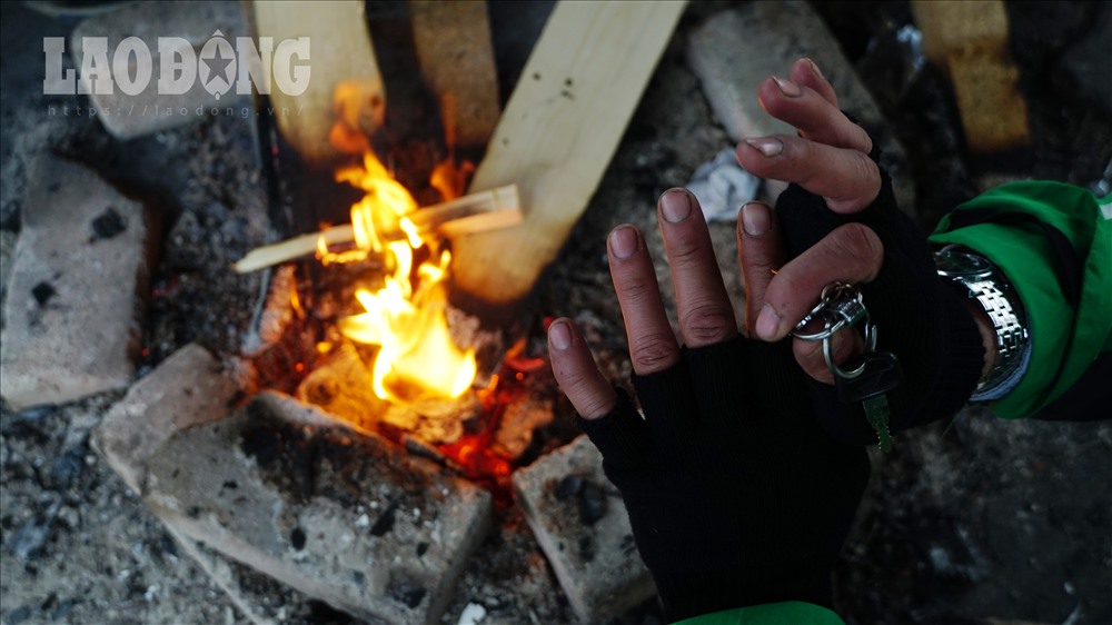 Những đôi bàn tay khắc khổ của người lao động hơ trên lửa, để tìm chút hơi ấm. 