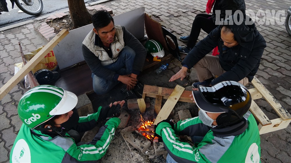 Một nhóm người làm nghề xe ôm, buôn bán đang ngồi quây quần cùng nhau bên đống lửa, nói dăm ba câu chuyện cũng xua bớt phần nào cái lạnh giá.