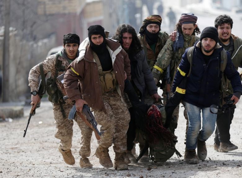 Các binh sĩ của Quân đội Syria Tự do được Thổ Nhĩ Kỳ hậu thuẫn đang lôi những binh sĩ bị thương ra khỏi khu vực giao tranh ở Rajo, Syria, ngày 3.3.2018.