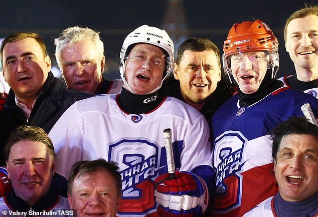Putin, đội mũ bảo hiểm và đeo găng tay, chụp ảnh với các cầu thủ trong trận khúc côn cầu bao gồm các thống đốc khu vực Alexei Dyumin (trái) và Dmitry Mironov (thứ ba bên phải).