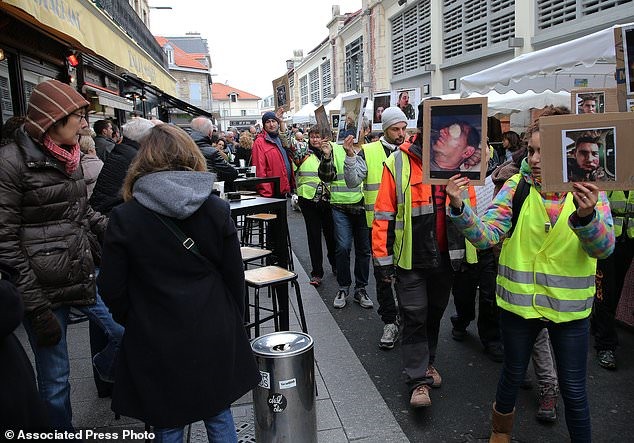 Người biểu tình mặc vest màu vàng giữ ảnh của những người mà họ nói là nạn nhân của bạo lực cảnh sát trong những tuần gần đây tại Pháp, ở Biarritz, tây nam nước Pháp, Chủ nhật, ngày 30 tháng 12 năm 2018. Ảnh: AP