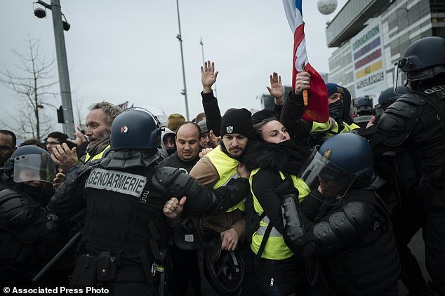 Các sĩ quan cảnh sát chống bạo động Pháp giữ lại những người biểu tình mặc vest vàng khi họ biểu tình trước mạng lưới truyền hình công cộng Pháp (France Tivi) tại Paris, Thứ Bảy, ngày 29 tháng 12 năm 2018. 