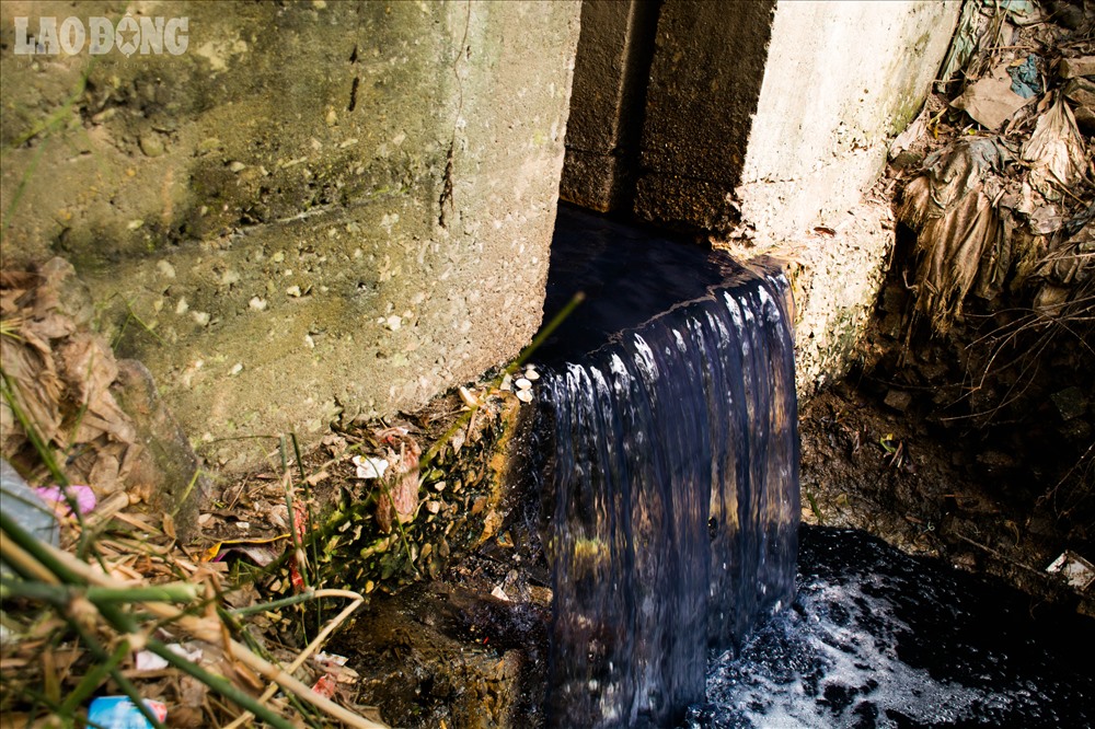 Màu nước đổ từ cửa mương ra sông Nhuệ.