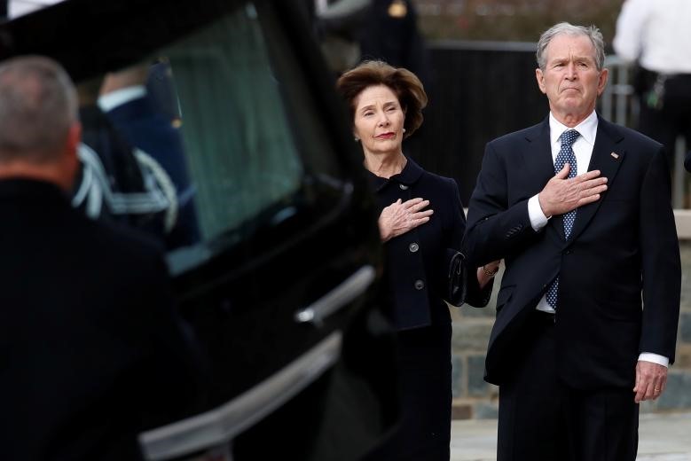 Khi linh cữu được đưa từ xe xuống, các thành viên gia đình ông Bush đứng bên cạnh và đặt tay lên ngực. Ảnh: Reuters.