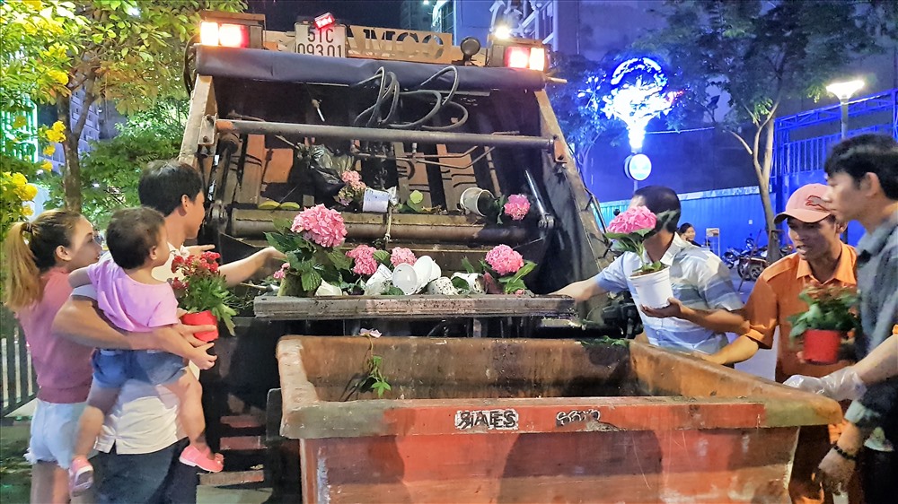Thấy nhiều chậu hoa đẹp đang nằm trên xe ép rác, nhiều người dùng tay với lại, cho vào túi nilon. Ảnh: Trường Sơn
