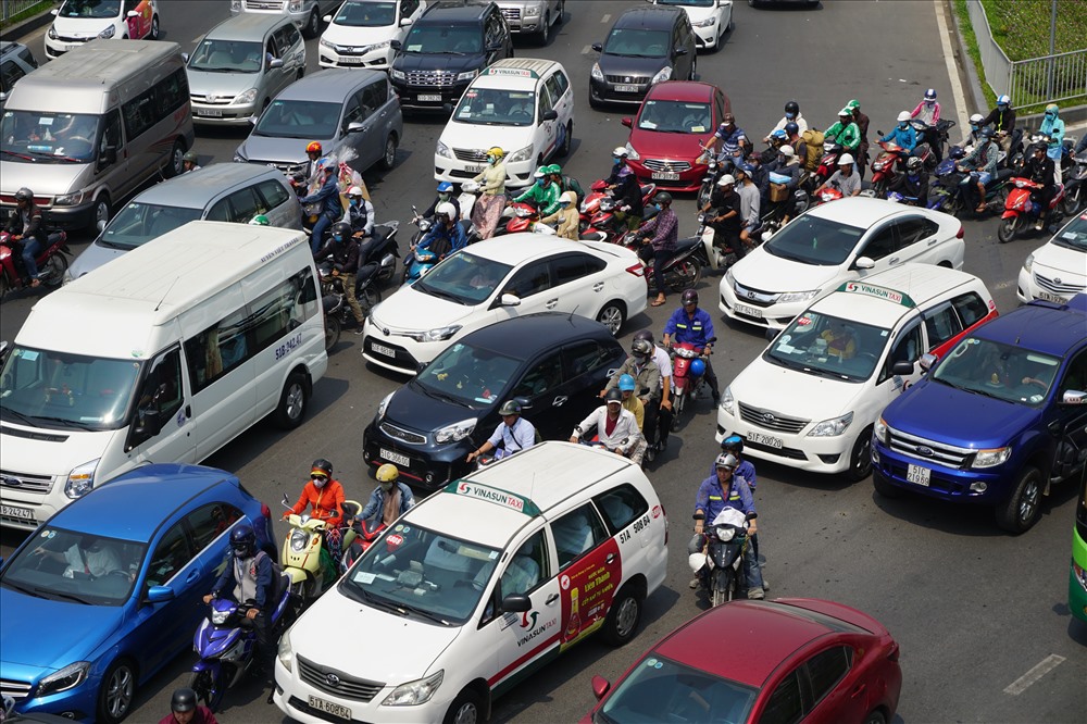 Giữa trưa nắng, hàng trăm người đi xe máy phải len lỏi giữa khoảng cách các ô tô tìm lối thoát.