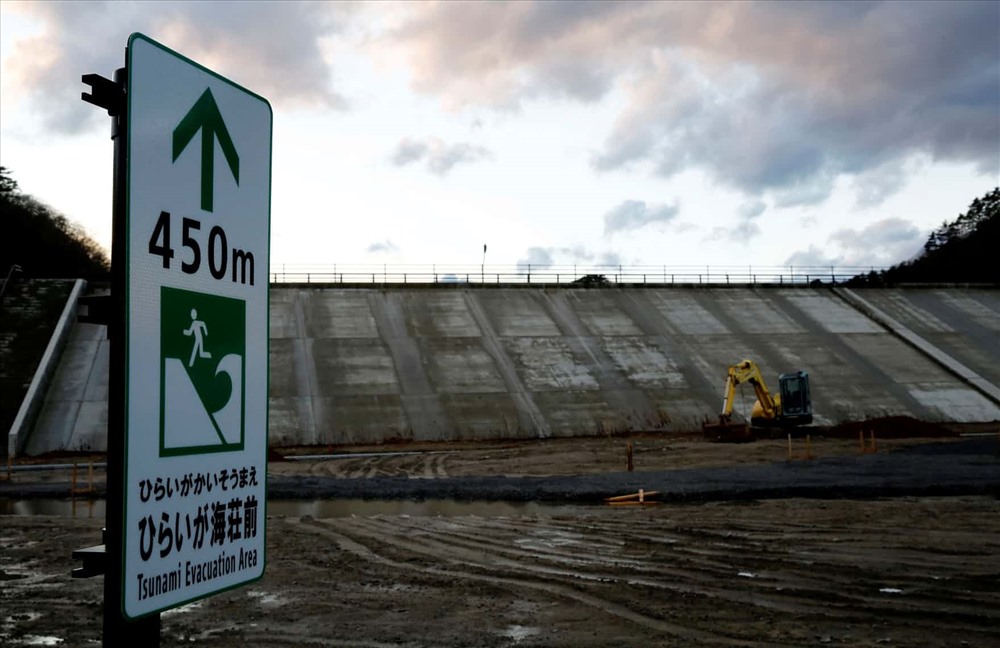 Biển báo chỉ dẫn sơ tán sóng thần trước bức tường biển ở Tanohata. Ảnh: Reuters
