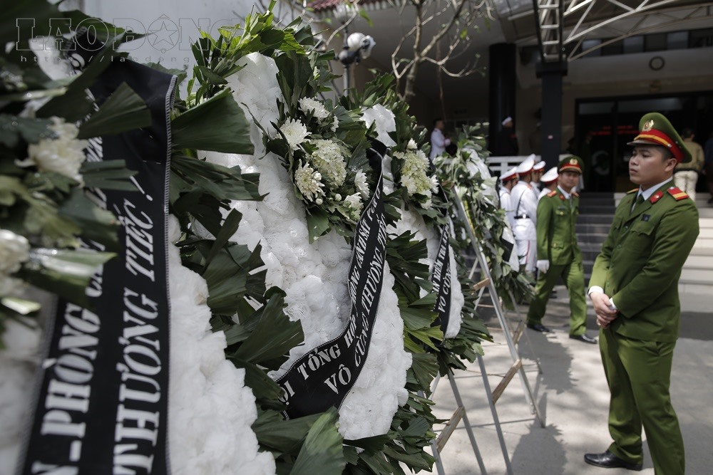 Dọc hai bên lối vào nhà tang lễ xếp kín hai hàng hoa trắng. Sự hi sinh của thượng sĩ Khánh khi tuổi đời còn trẻ khiến đồng đội và người thân vô cùng đau xót.