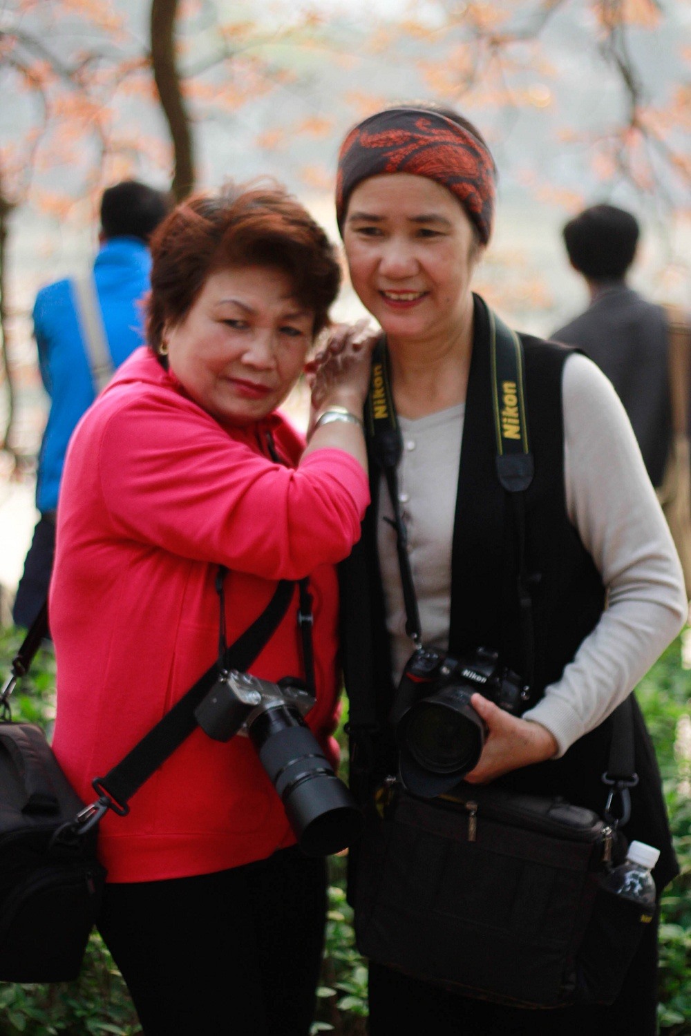 Hai nhiếp ảnh gia nữ cùng chụp kỉ niệm với bức nền phía sau là tán bằng lăng.