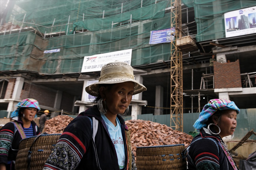 Những người phụ nữ dân tộc đi ngang qua một công trình lớn đang thi công trong thị trấn. Dường như đối với họ, sự xuất hiện nhan nhản của những chiếc máy cẩu, máy xúc đã trở nên quá đỗi bình thường.