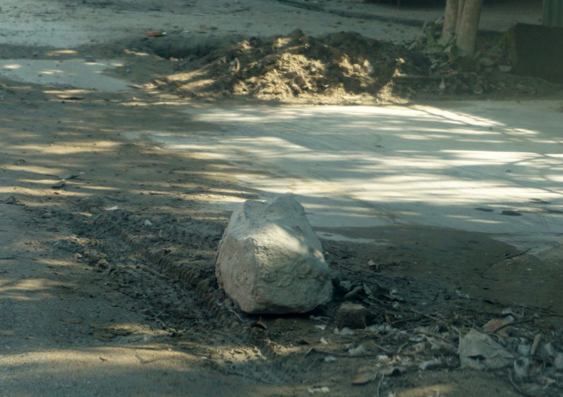 Một cục đá được người dân đặt trên đường làm “báo hiệu” các đoạn sình lầy (ảnh: Tr.L-Q.Đ)