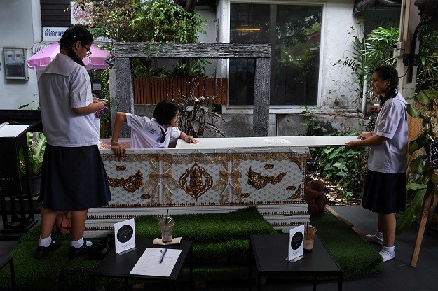Một thiếu niên người Thái trèo ra khỏi quan tài sau khi thử nằm trong chiếc quan tài màu trắng tại quán cà phê ý niệm về cái chết. (Ảnh: AFP)