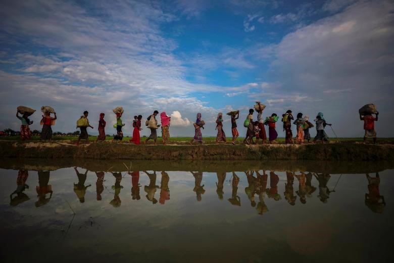 Hình ảnh dân tị nạn Rohingya phản chiếu qua làn nước mưa dọc theo con đê cạnh ruộng lúa, sau khi chạy trốn khỏi Myanmar vào Palang Khali gần Cox's Bazar, Bangladesh, ngày 02/11/2017. (Ảnh: Reuters)