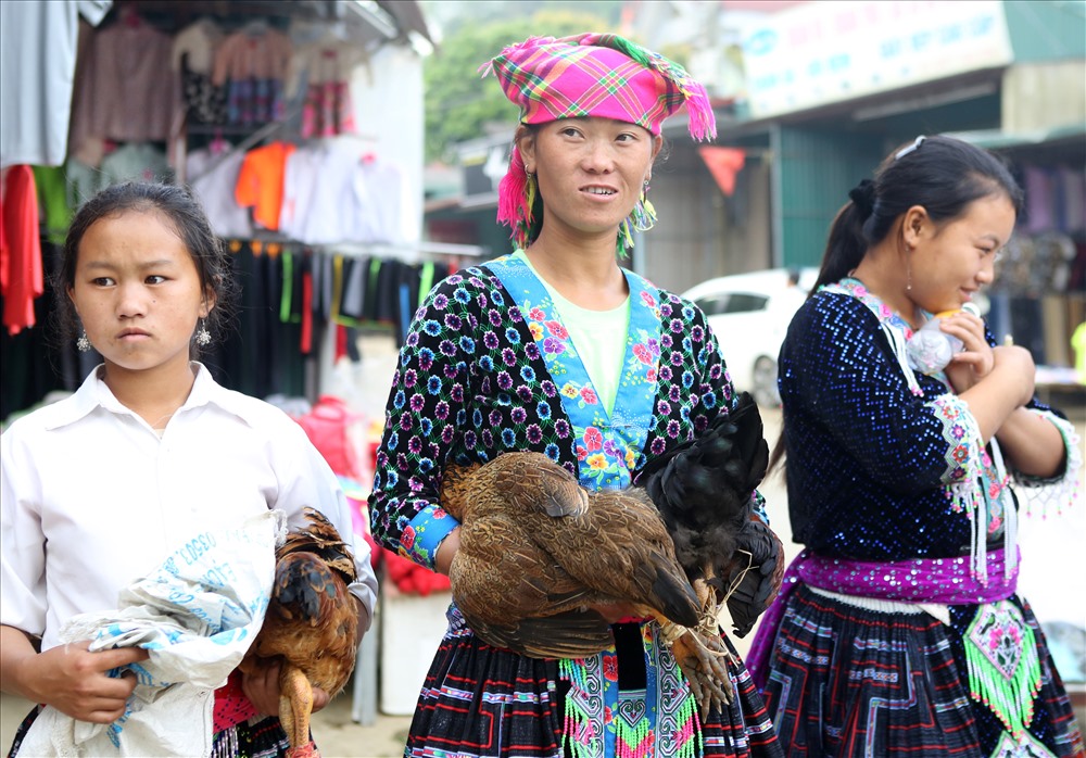 Những người phụ nữ Mông ở xã Tả Lèng ôm gà xuống chợ bán. Hàng hóa ở chợ chủ yếu được bà con tự sản xuất và mang đến chợ mua bán.