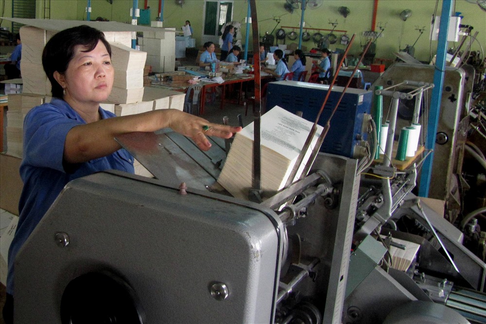 Chị Huỳnh Thị Danh với hình minh họa sáng kiến “Làm sách bìa cứng gáy tròn bằng ống nước”. Ảnh: NHÂN VẬT CUNG CẤP