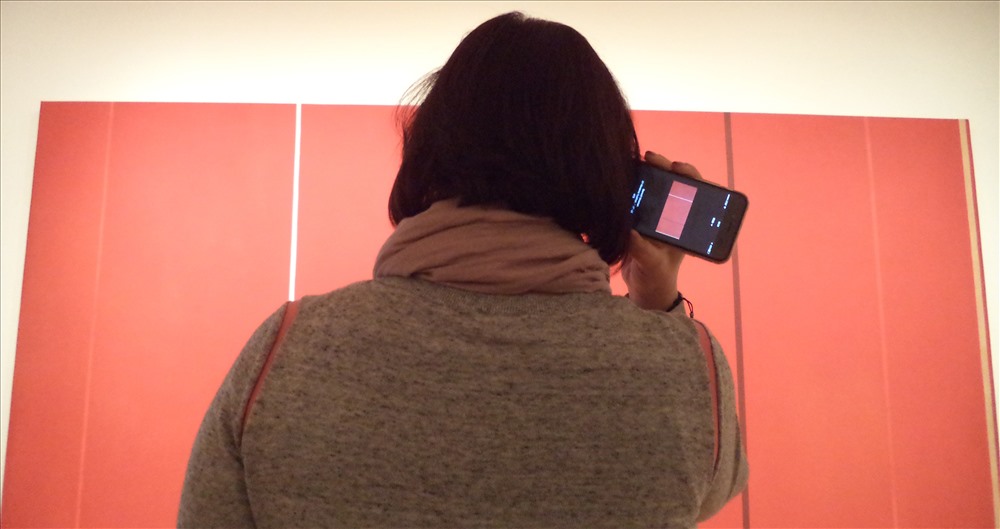 Tại MOMA New York. Thưởng lãm tranh trừu tượng ‘Vir Heroicus Sublimis (2) Barnett Newman vẽ năm 1951. Cái hay là khách có thể  sử dụng công nghệ hiện đại tại bảo tàng nghe giới thiệu, phân tích về bức tranh.  Ảnh: TUYỀN LINH - TÂM TRƯƠNG