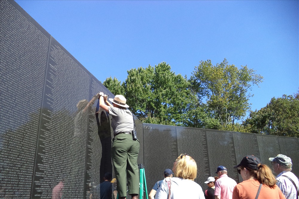 Nhân viên Đài tưởng niệm tô lại tên một người lính tử nạn từ bức tường vào tờ giấy giúp thân nhân của người lính tử nạn.
