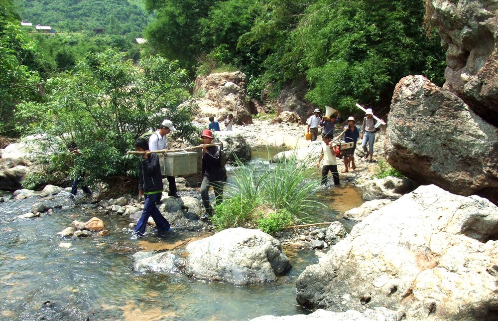 Thanh niên bản làng xã Hướng Sơn giúp sức gồng gánh máy móc, thiết bị qua suối. Ảnh: TH.                                                                      