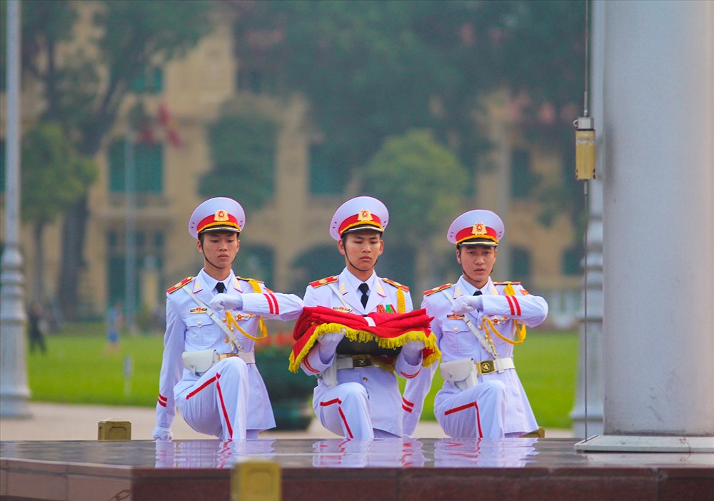 Khi đội tiêu binh gồm 34 chiến sĩ đi từ phía sau Lăng Bác tiến đến cột cờ. Ba chiến sĩ đội hồng kỳ sẽ bước lên bục chuẩn bị các nghi thức thượng cờ, cũng là lúc cửa Lăng Chủ tịch Hồ Chí Minh bắt đầu mở.